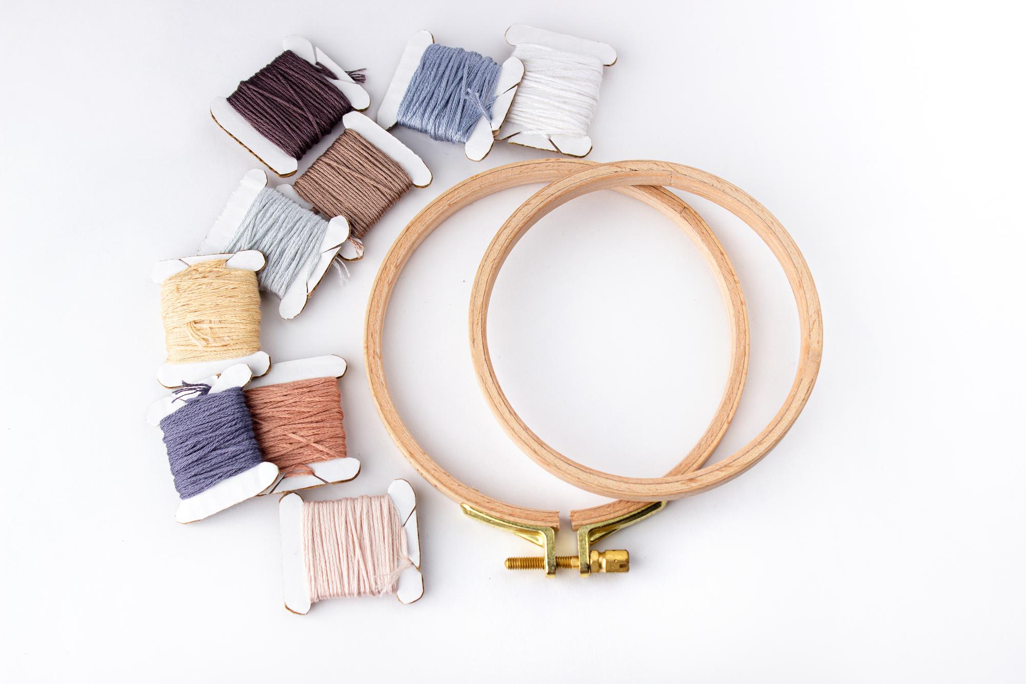 Set of embroidery tools and threads on white workspace